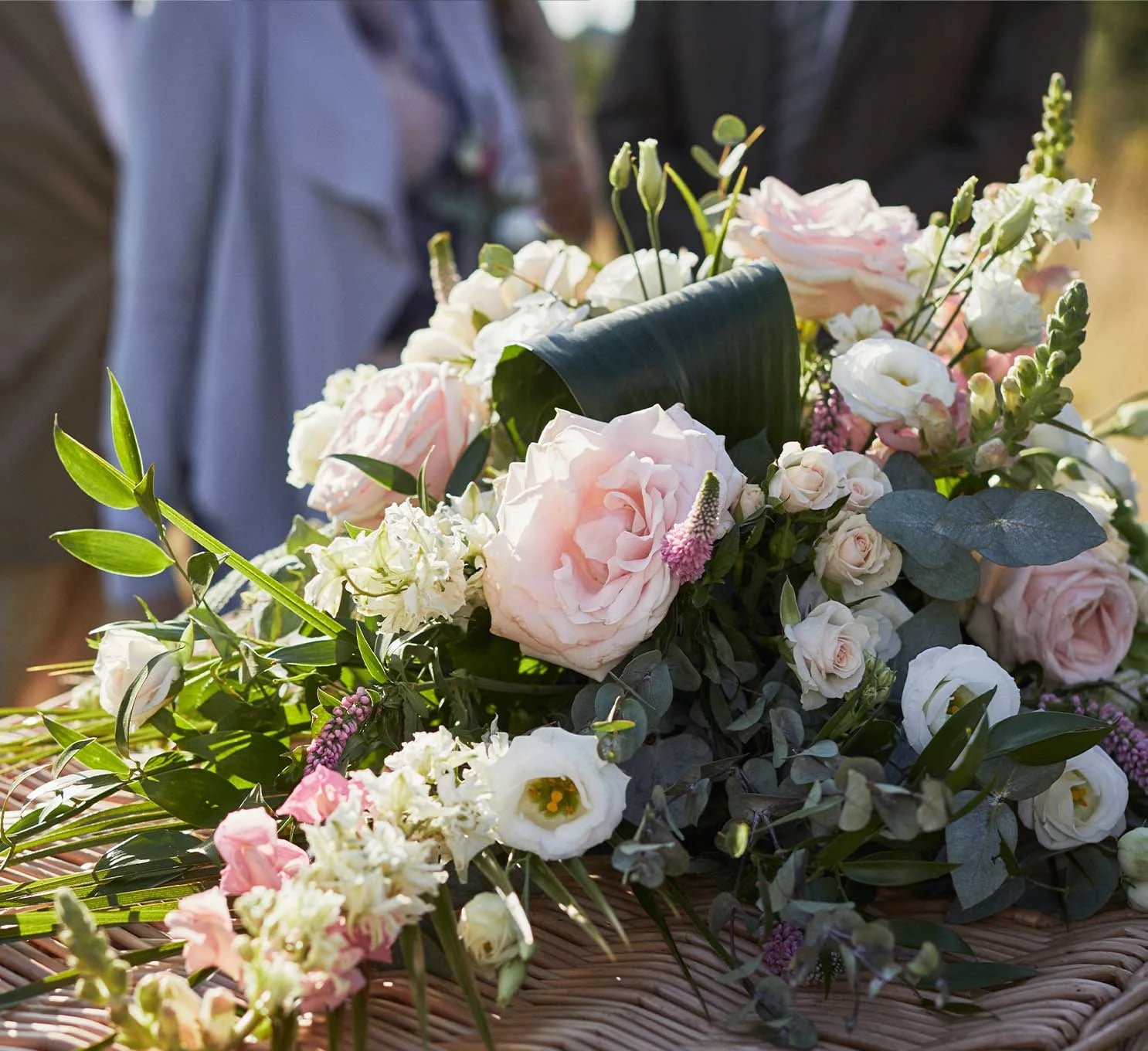 A decorative bouquet of flowers resting on a wicker coffin